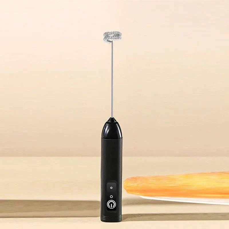 Black handheld electric coffee milk frother with spiral whisk on beige background